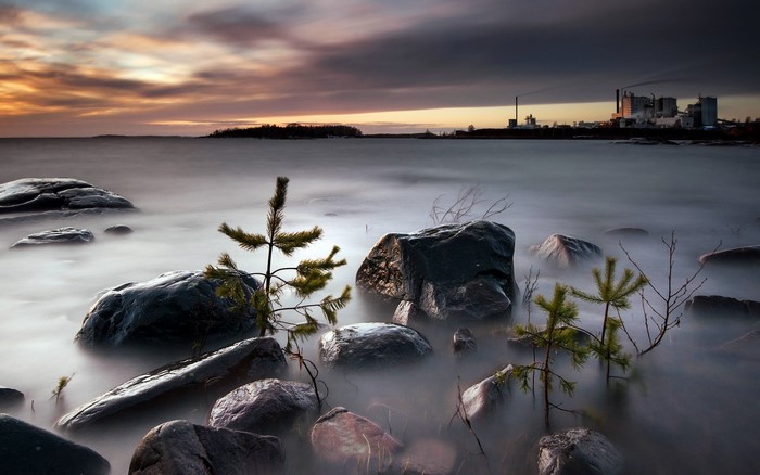 Rocky shore with industrial background at sunset