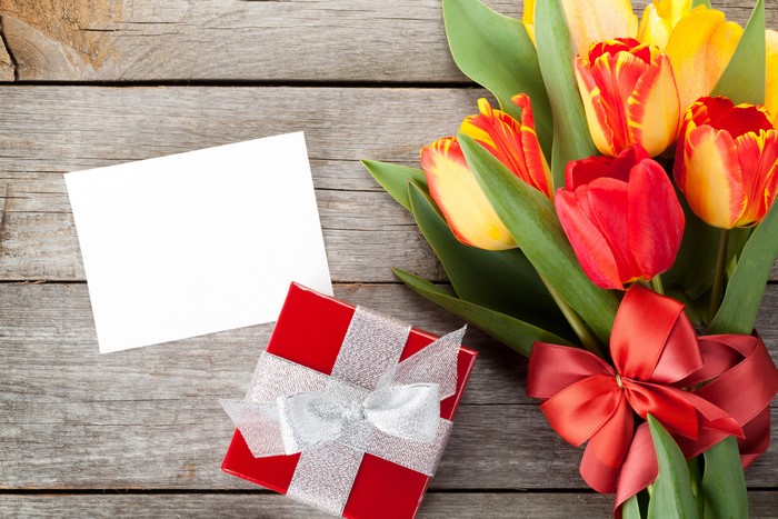 Tulip bouquet with gift and card on wooden table