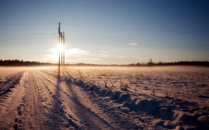 Winter road with power lines at sunrise
