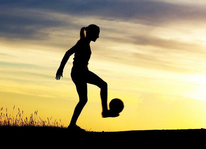 Silhouette of a girl playing soccer at sunset