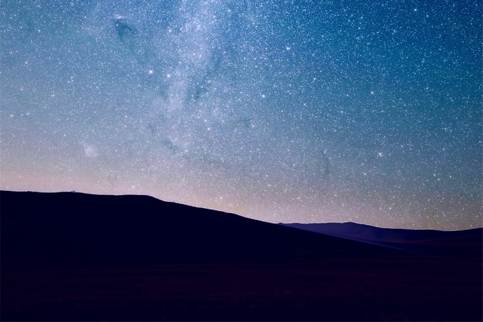 Night sky full of stars over dark hills