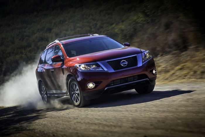 Red Nissan Pathfinder driving on a dirt road