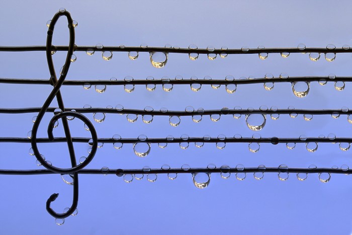 Treble clef with water drops on a blue sky background