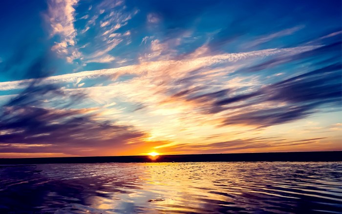 Sunset over a calm body of water with dramatic clouds