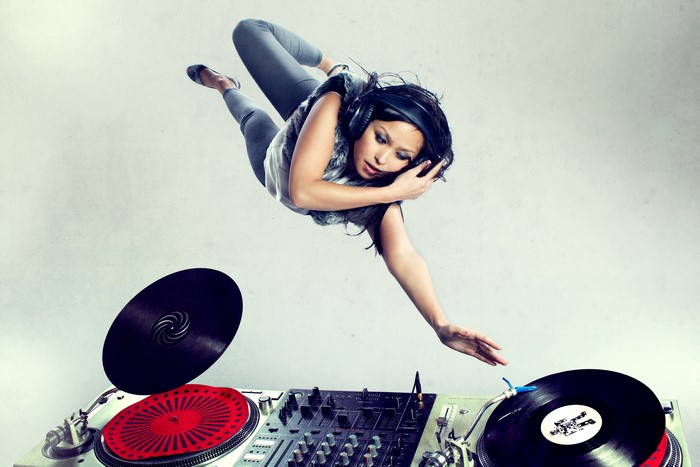 DJ girl with headphones jumping over turntables