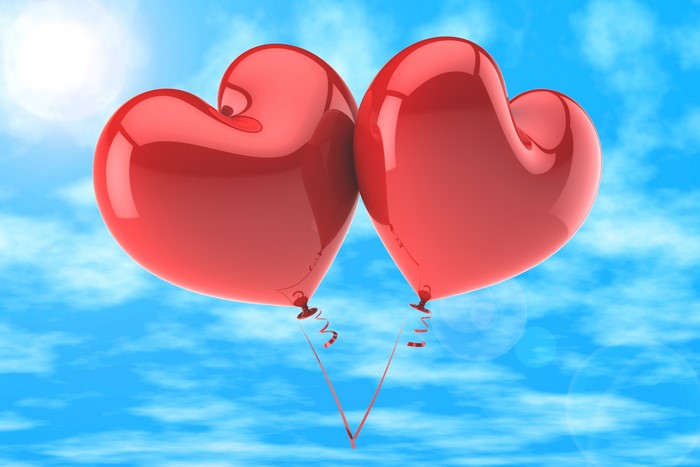 Two red heart balloons in the sky