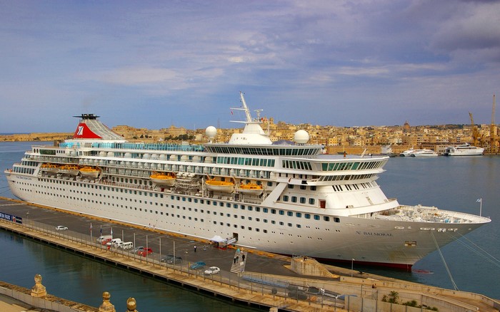 Cruise liner docked in a harbor with a city in the background