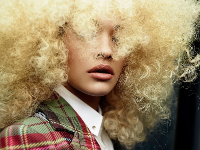 Rita Ora with blonde afro hair and plaid jacket