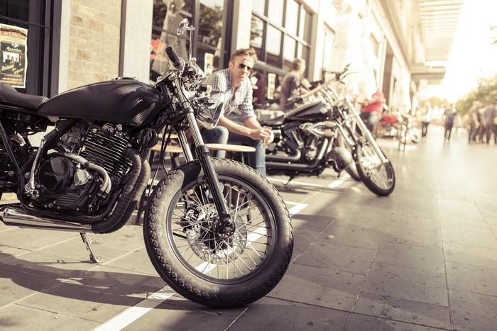 Cafe racer motorcycles parked outside a building with people