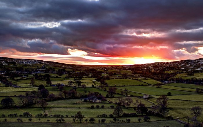 Sunset over rolling green fields and a village