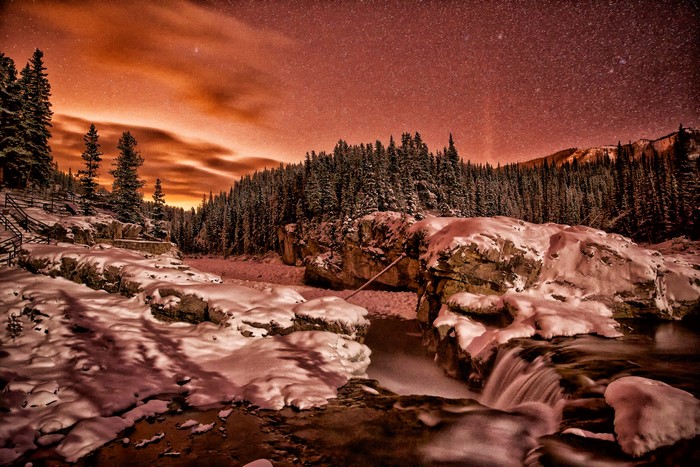 Winter night sky over a snowy forest and river