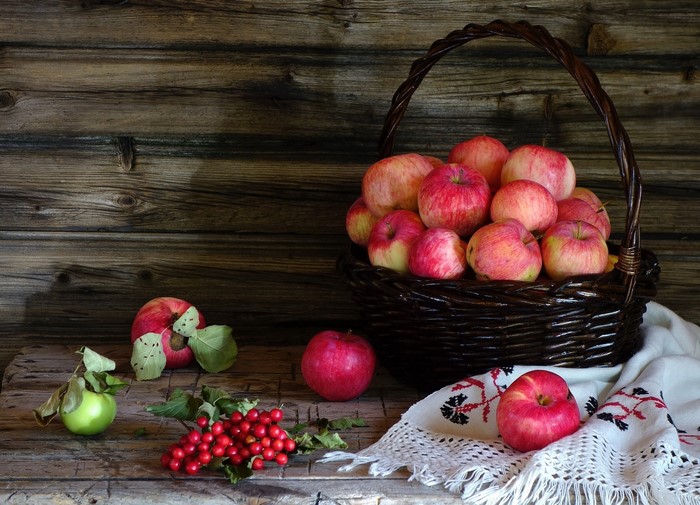 Apples in a wicker basket with berries and cloth