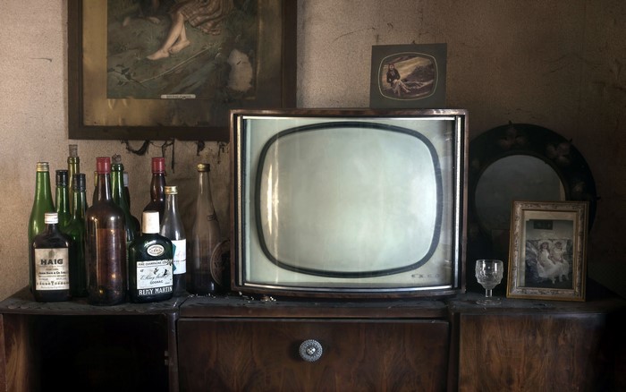 Retro TV set with bottles and framed pictures