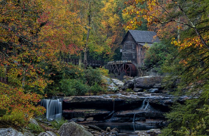 Old mill with water wheel in autumn forest