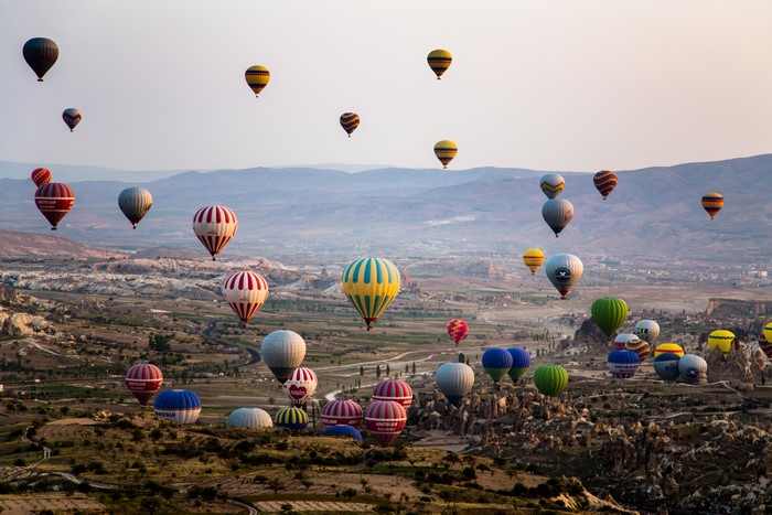 Many hot air balloons over a valley