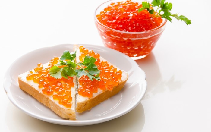Toast with red caviar and parsley on a plate