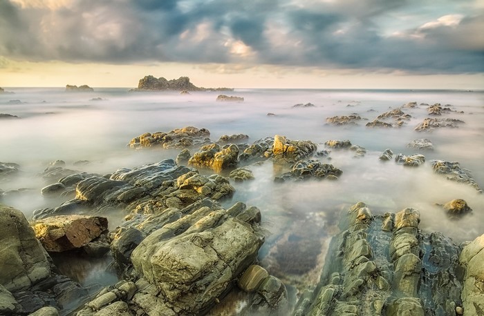 Rocky coastline with misty ocean and dramatic clouds