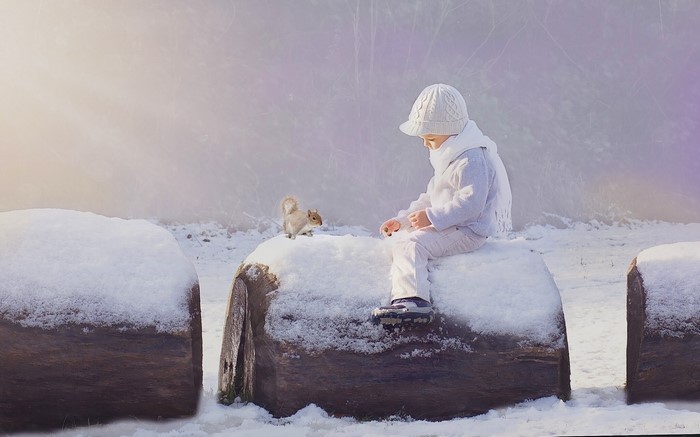Child feeding a squirrel in the snow