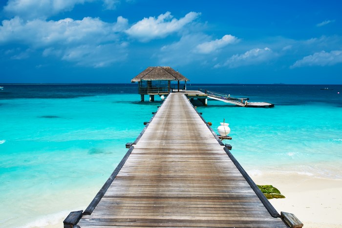 Wooden pier leading to a hut over turquoise water
