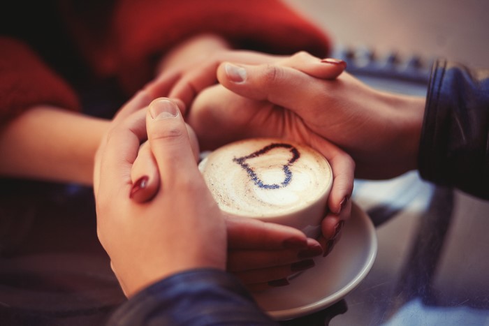 Couple holding a coffee cup with a heart