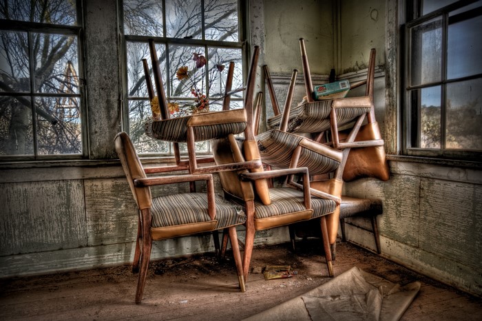 Stacked chairs in an abandoned room with windows