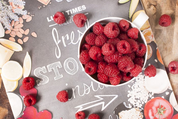 Raspberries in a bowl on a chalkboard