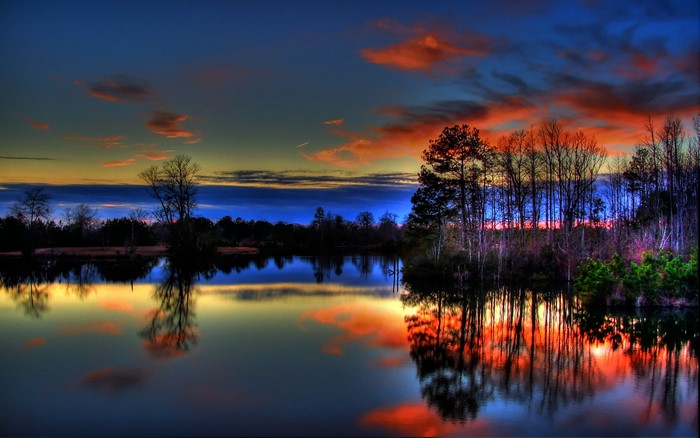 Lake reflecting sunset sky with trees