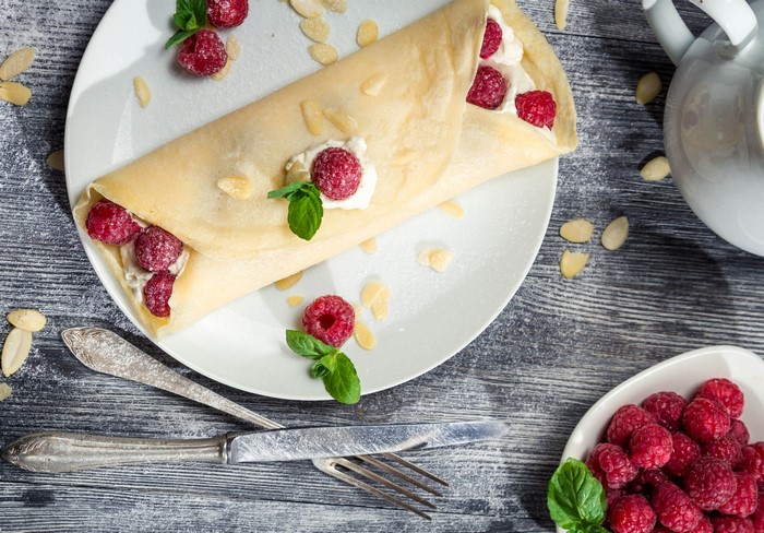 Pancake with raspberries and cream on a plate