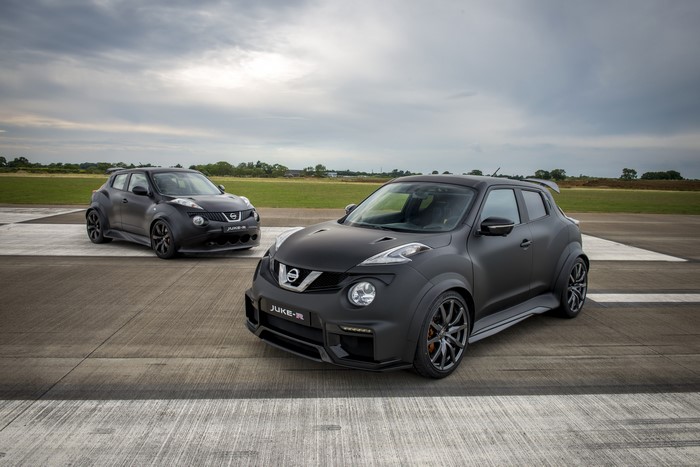 Two matte black Nissan Juke-R 2.0 cars on a runway