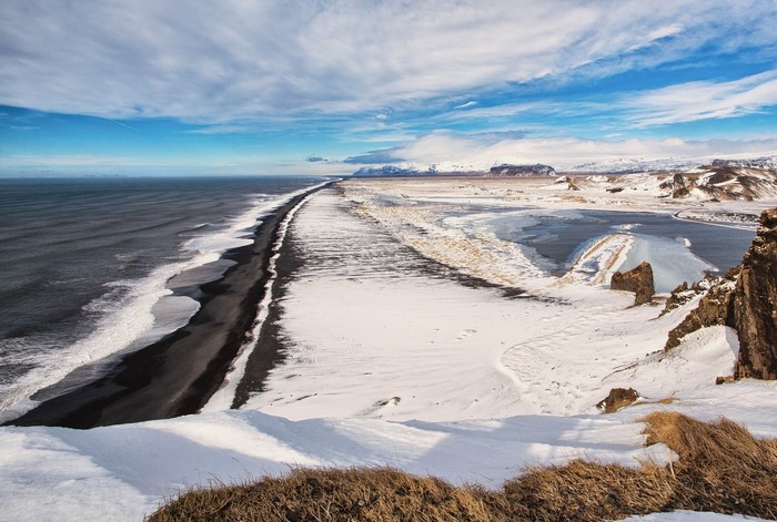 Snowy black sand beach with ocean and mountains