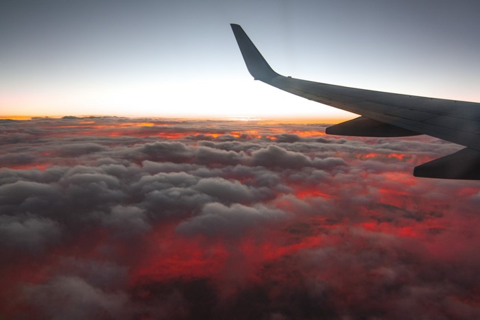 Airplane wing over clouds at sunset