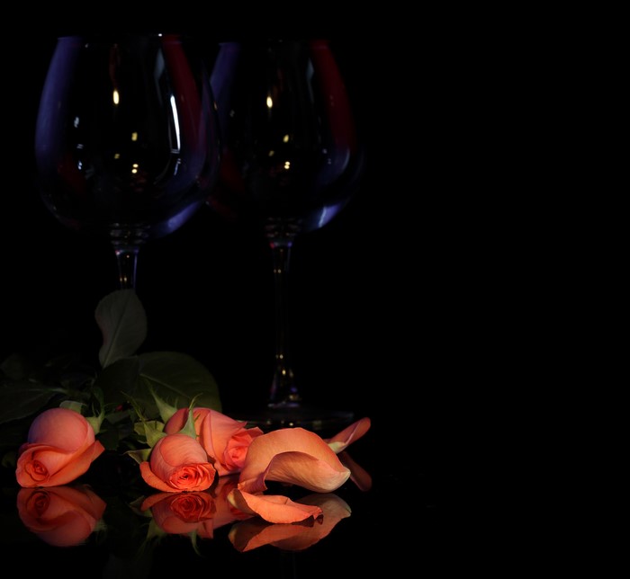 Two wine glasses with roses and petals