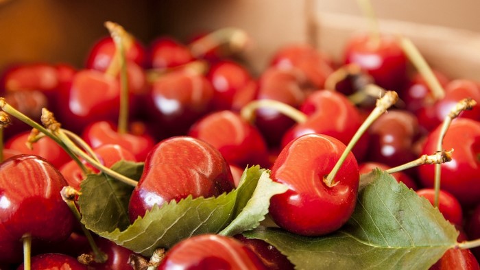 Close-up of fresh red cherries with green leaves