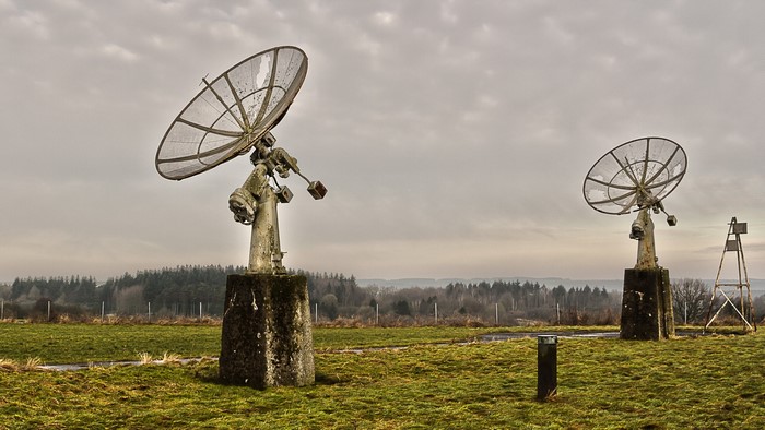 Two old satellite dishes in a field