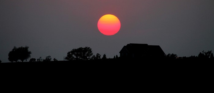 Sunset over a silhouetted landscape with a house
