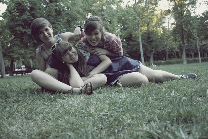 Three smiling girls sitting on grass