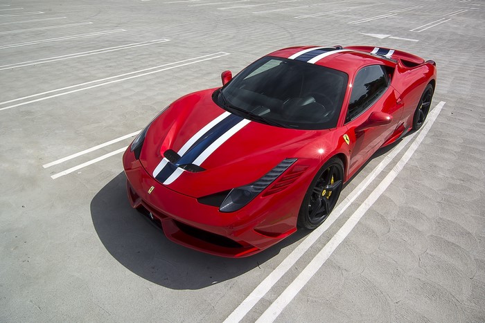 Red Ferrari 458 Speciale with racing stripes in parking lot
