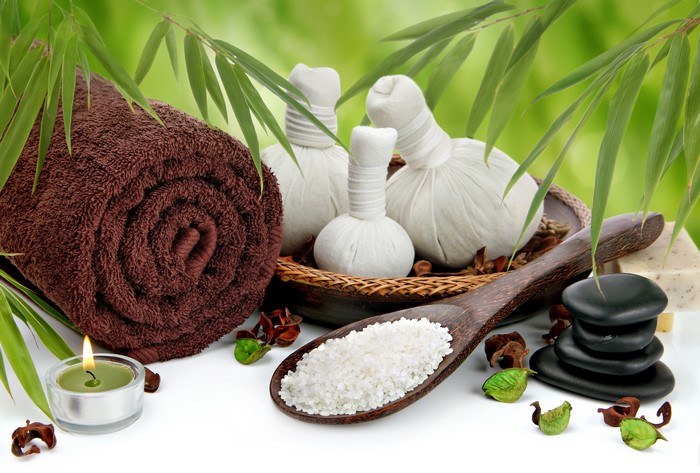 Spa items with rolled towel, massage stones, and candle