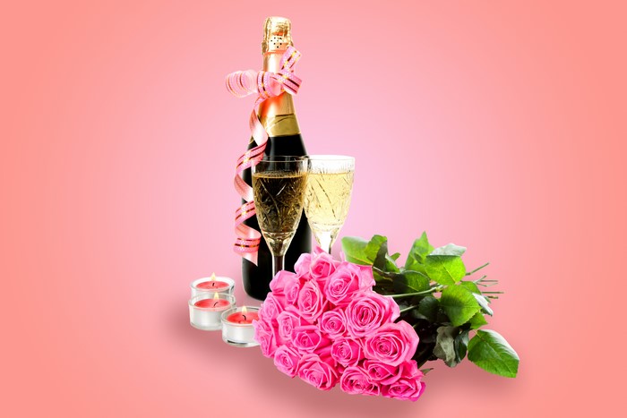 Champagne bottle with glasses, pink roses, and candles