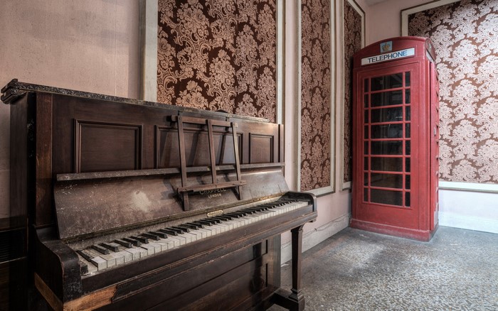 Old piano and red telephone booth in a room