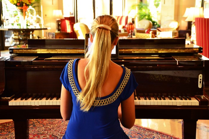 Blonde girl playing a grand piano