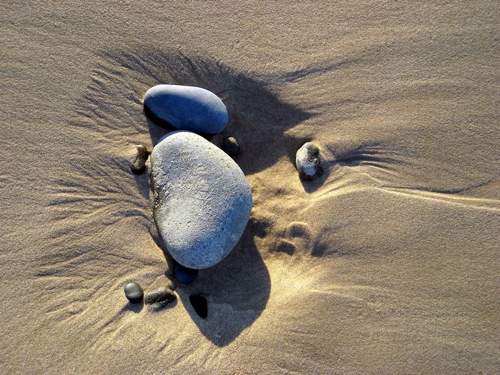 Smooth stones on wet sand with ripples
