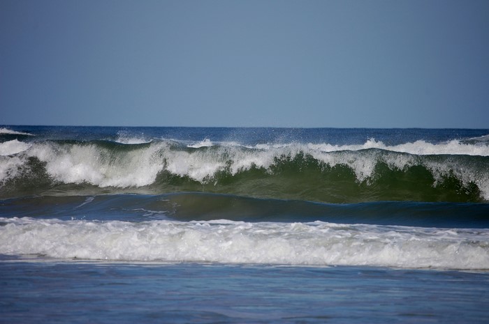Ocean waves crashing under a clear blue sky