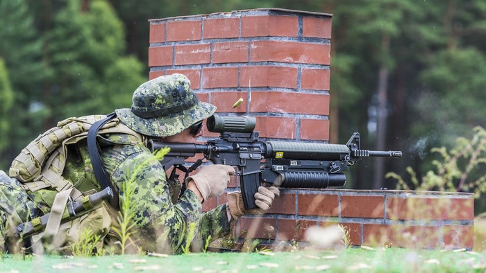 Soldier firing an assault rifle with a grenade launcher