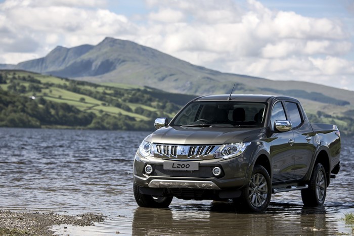 Mitsubishi L200 pickup truck by a lake with mountains