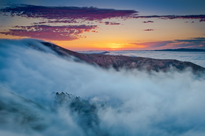 Foggy mountain sunrise with colorful clouds