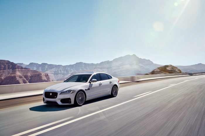 2015 Jaguar XF S AWD driving on a road with mountains
