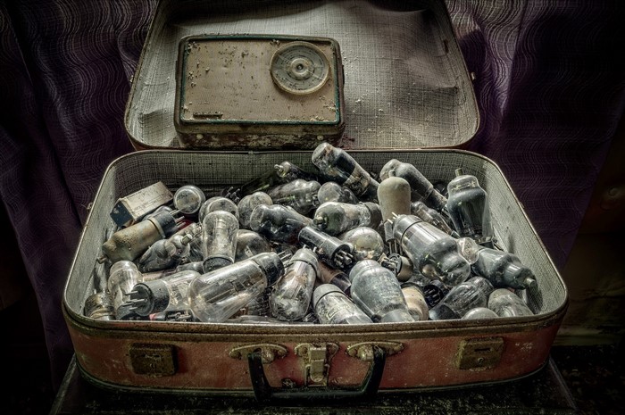 Old suitcase filled with vacuum tubes and a vintage radio