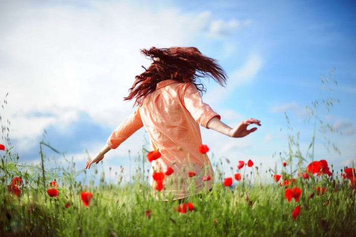 Woman with red hair in a poppy field
