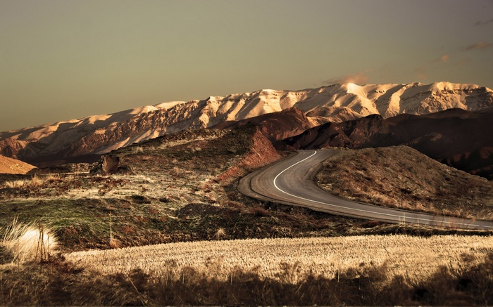 Winding road through mountainous landscape with snow-capped peaks